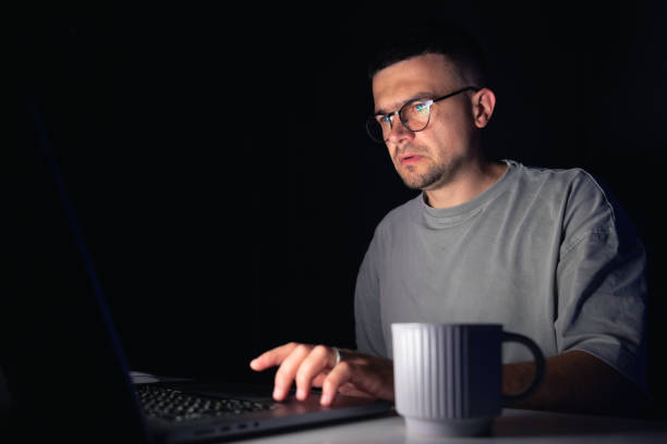 istock Young man works at the computer at night. 2175664116