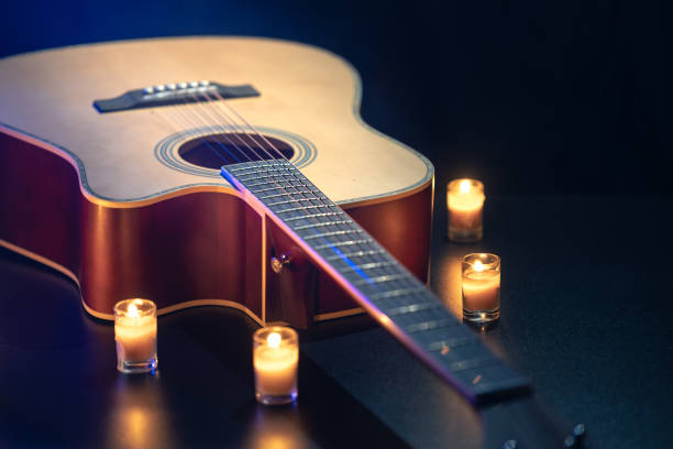 istock Acoustic guitar on a black background with candles. 2175664363
