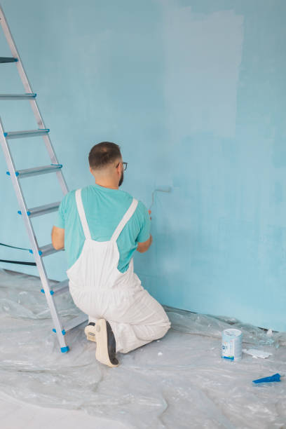 istock Painter in white overalls painting a blue wall indoors 2175664766