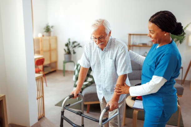 Female nurse helping senior man with mobility walker at home