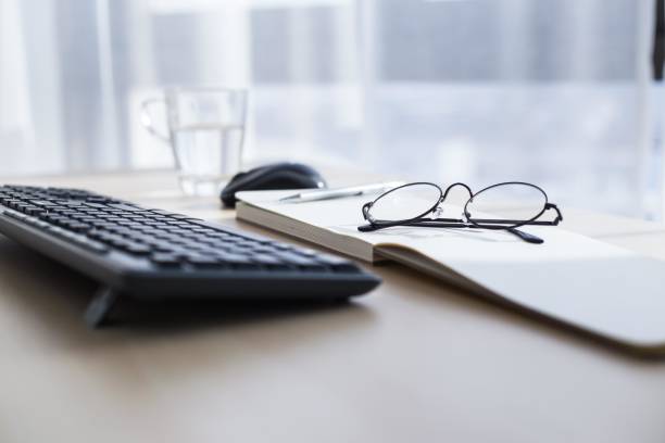 istock Black keyboard, mouse, glasses and notebook on wooden table in home office 2175668139
