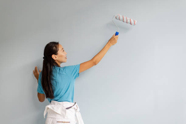 istock Woman painting a wall with a roller brush indoors. 2175668230