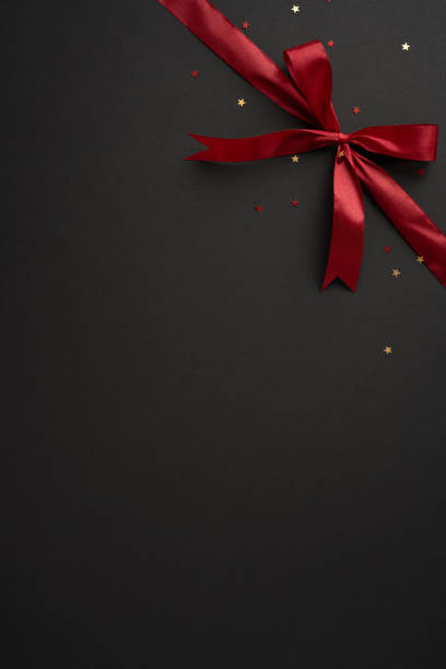 istock A stylish vertical red ribbon bow adorns a black backdrop, scattered with small stars, creating a festive and elegant atmosphere 2175669901