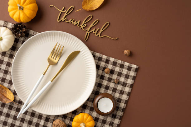 istock Top view of a stylish Thanksgiving table setting featuring a plaid napkin, white plate, and elegant cutlery with a thankful message and autumn decorations 2175669908