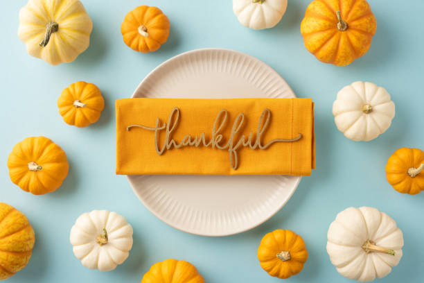 istock Festive Thanksgiving table setting with a thankful message on a napkin surrounded by mini pumpkins on a blue background 2175669912