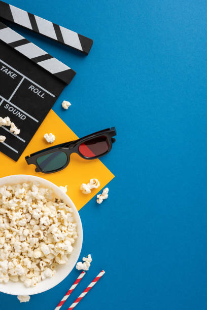 Popcorn and 3D glasses with a clapperboard on a vertical vibrant blue background. Ideal for movie, entertainment, and cinema concepts