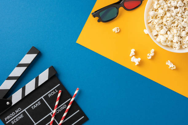 istock Flat lay composition of cinema essentials including popcorn, 3D glasses, and a clapperboard on colorful backgrounds 2175669941