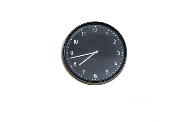 istock Black wall clock with white numbers and hands on a plain white background. 2175672165