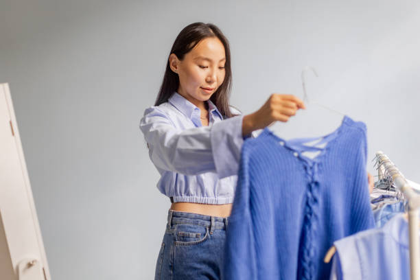 istock Young woman explores clothing rack for selection 2175673151