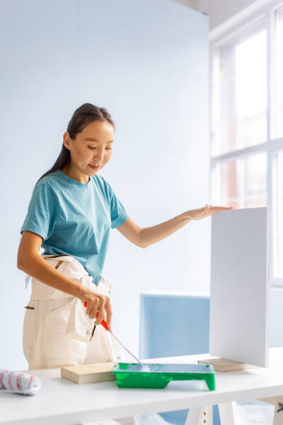 istock Person painting vertically with roller in bright space 2175677127