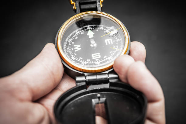 A hand clasping a compass, perfect for navigation, outdoor activities, adventure travel, and exploration. Ideal for hiking enthusiasts seeking direction in wilderness and nature.