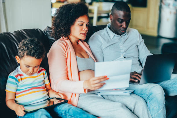 istock Pregnant woman with her husband at home analyzing bills 2175682042
