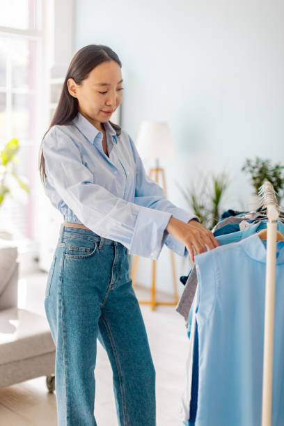 istock Woman examining clothes on a rack at home setting. 2175685285