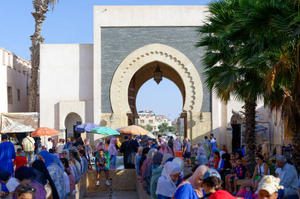 Agadir, Morocco, 08 13 2024 : Moroccan people in the bazaar called Souk El Had. Islamic architecture : door. Palm trees.