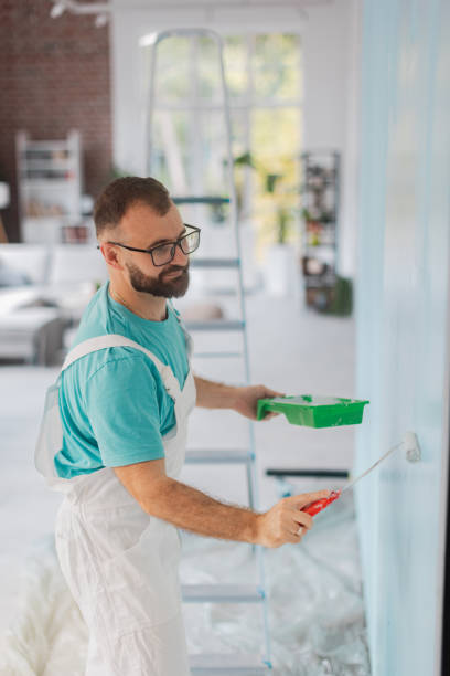 istock Artist in overalls paints wall turquoise with roller 2175686043