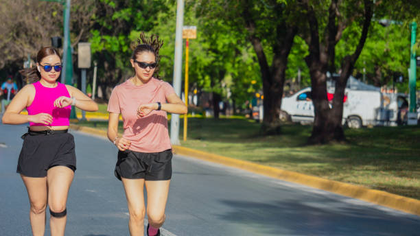 istock Two Latina women checking smartwatches while running outdoors 2175687376