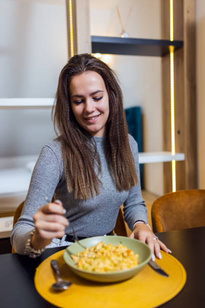 istock Woman eating mac and cheese in her apartmen. 2175688129