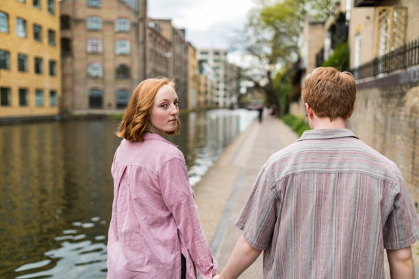 istock Young couple holding hands walking by canal looking back over shoulder 2175689890