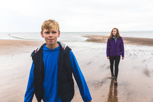 istock Boy and woman at beach on a rainy day 2175689893
