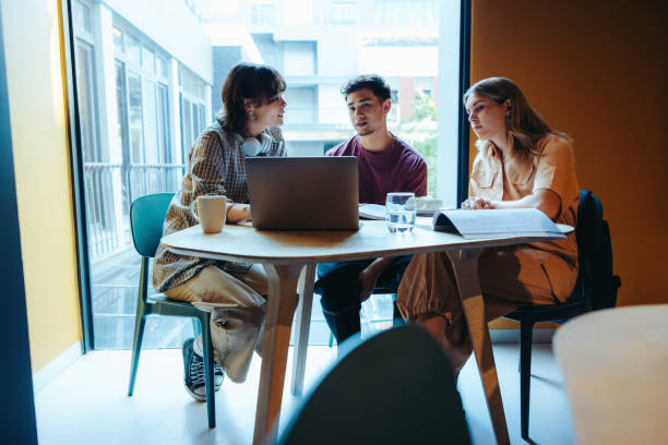 istock Colleagues engage in a productive discussion in a shared office space, collaborating at a table with a laptop and documents, fostering teamwork and creativity. 2175699822