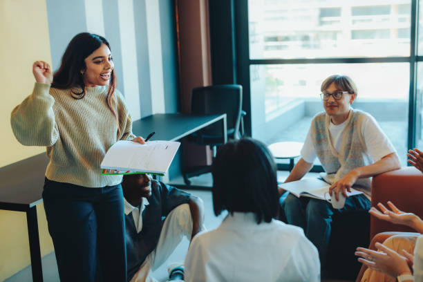 Confident student presenting a project to classmates in a modern classroom setting with attentive audience A student confidently presents a project to classmates in a modern classroom environment, with an engaged and attentive audience. presentation speech stock pictures, royalty-free photos & images