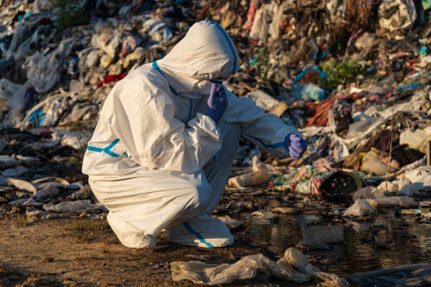 istock Dressed in protective gear, a worker crouches at a landfill, analyzing waste amidst a backdrop of piled trash, shining in the soft morning light, addressing urgent environmental challenges 2175704061