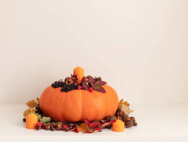 istock A large pumpkin with candles and autumn decorations on white table with copy space. Thanksgiving day concept. Autumn leaves, berries, acorns and chestnuts. 2175704594