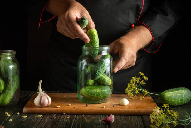 istock Preserving cucumbers in a jar by the chef's hands for long-term storage. The concept of pickling vegetables on the kitchen table 2175705347