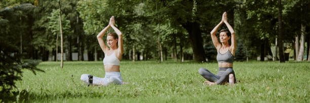 istock Women Sitting in Lotus Pose on Grass 2175707160