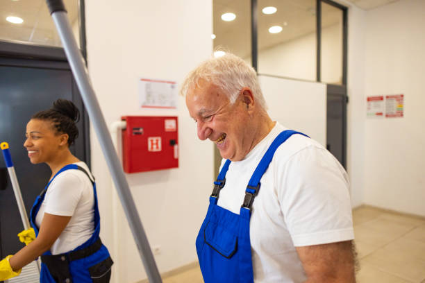 istock Cheerful male and female custodians walking in school hall with working tools 2175709963