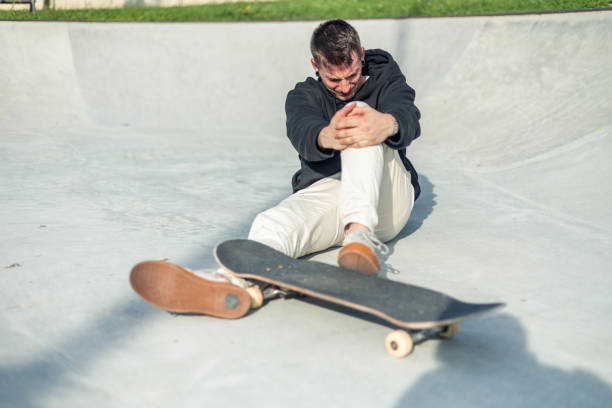 istock Skater with pained expression holding their knee after an accident during a session in skate park 2175710821