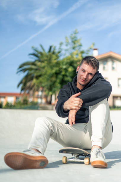 istock vertical Relaxed skater posing for the camera while sitting on their board in the skate park 2175710843