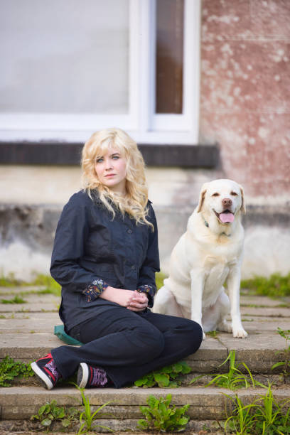 Teenage blonde wearing casual clothes resting with her dog. Focus on girl.