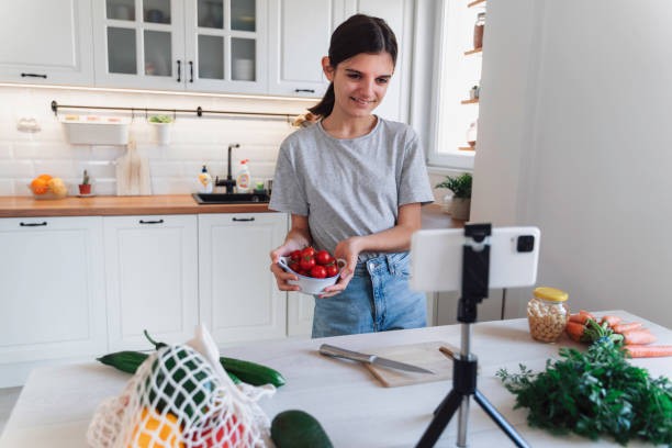 istock Girl films cooking video in kitchen with vegetables 2175724228