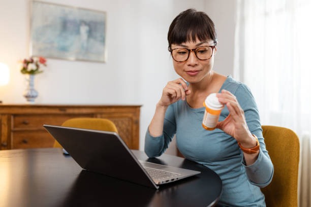 istock Japanese woman reading pill bottle instructions and using laptop 2175724645