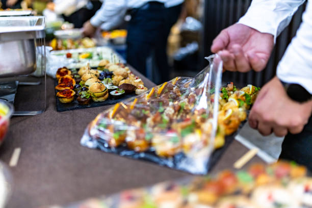 istock A caterer unwraps assorted appetizers on a serving platter during a bustling event in an upscale venue 2175726565