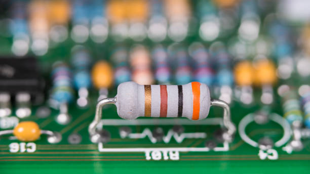 Closeup a white resistor with standard colored code on a green printed circuit board
