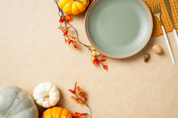 istock Autumn flat lay with pumpkins, plate, nuts, and foliage on a neutral background. Perfect for fall, Thanksgiving, and culinary concept. 2175732492
