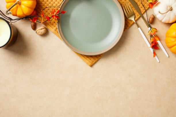 istock Elegant autumn table setting with a plate, golden cutlery, and festive fall decorations like pumpkins and leaves. Thanksgiving dinner concept 2175733295