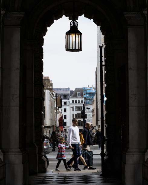 London, England, Apr 30 2023: Father and daughter walking outside in London, framed by an old arcade entrance