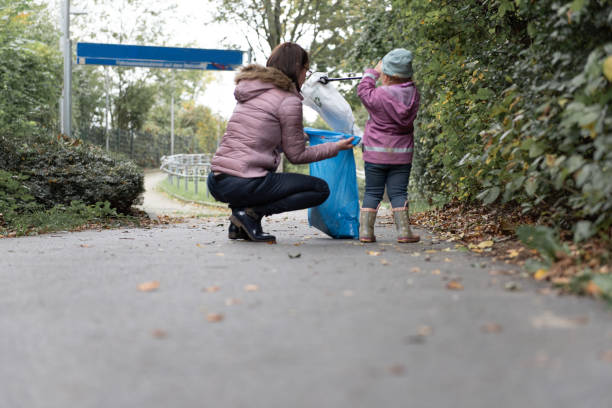Mother and child collect garbage in a park stock photo