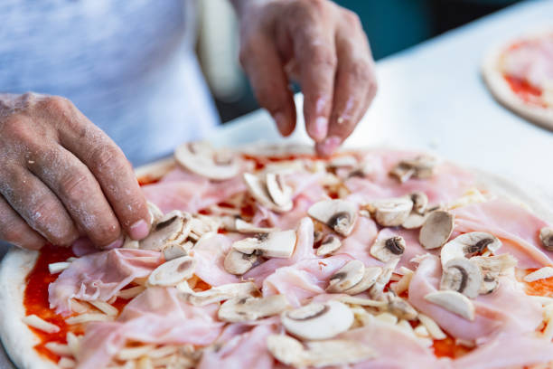 3D Male Chef Cooking. A male chef is standing carrying a pizza in his left hand and raising his right hand with his thumb and index finger together as a sign of \