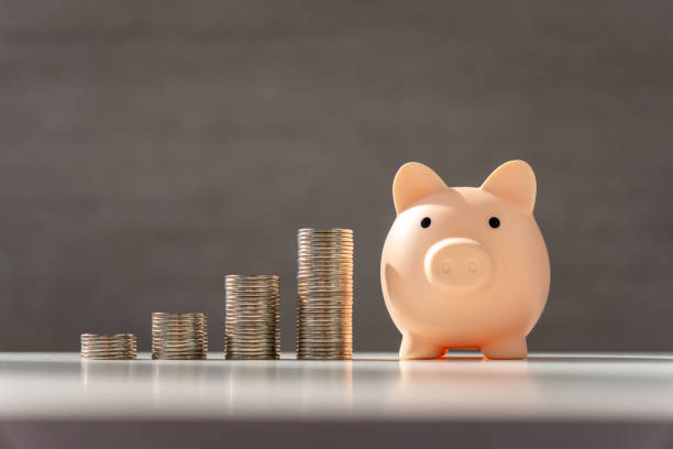 istock Silver coins stack and pink piggy bank on grey background with growth, Coins arranged as graph. Concept of money saving and business finance. 2175763674