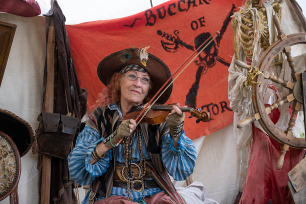 Dana Point, CA, USA - September 15, 2024: A female pirate plays the violin in a pirate camp during a historical reenactment on the Ocean Institute’s 40th annual Maritime Festival held in Dana Point Marina.