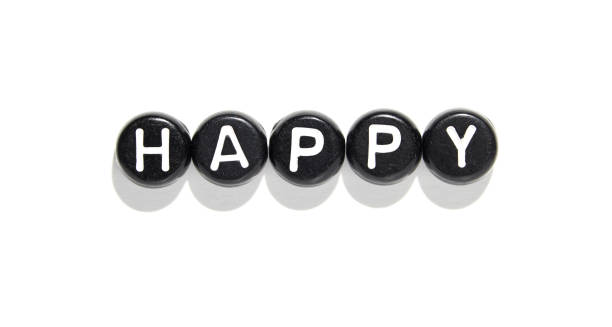 Black stones with white letters forming the word happy on white background
