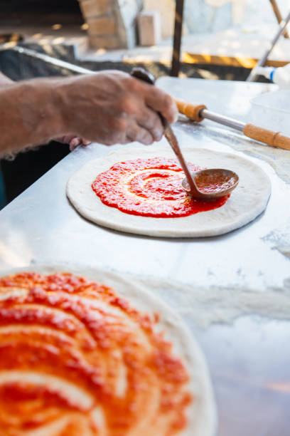 istock Pizza chef spreading tomato sauce on the pizza 2175769950