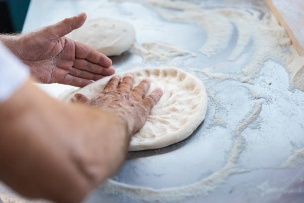 Pizza Chef (Pizzaiolo) Making Pizza in Outdoor Brick Oven Kitchen on a Sunny Day