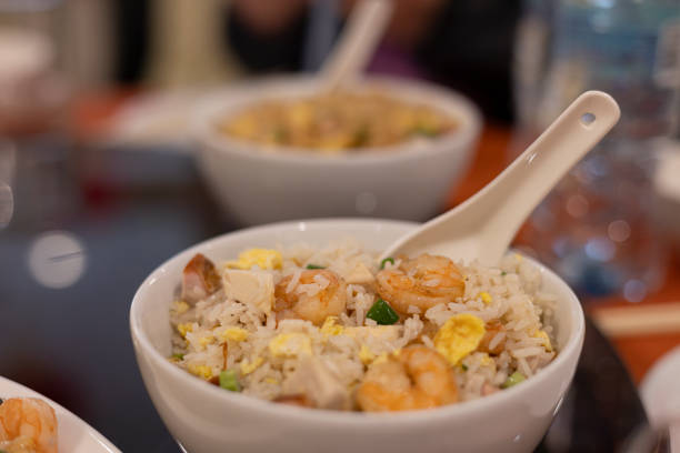 Young woman eating fresh prawn yee mee in plate with chopsticks