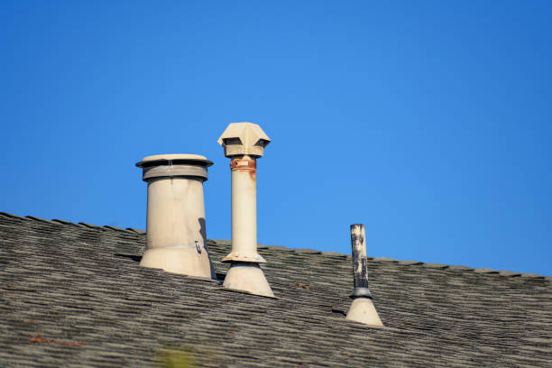 istock A rooftop features three distinct metal vents, including a cylindrical vent, a rusted pipe, and a geometric-shaped exhaust vent. 2175796452