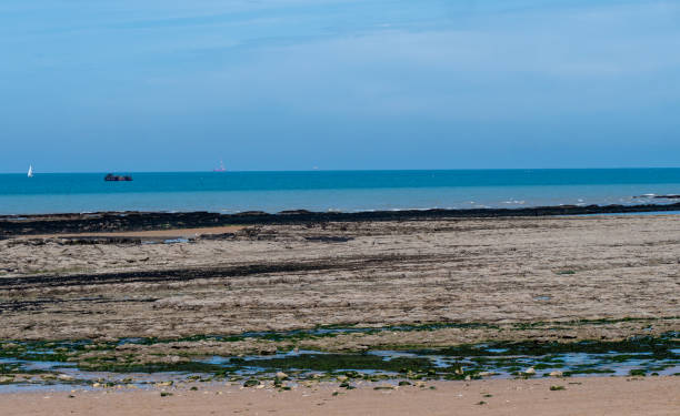 istock A beach with a boat in the distance and a blue sky 2175804759